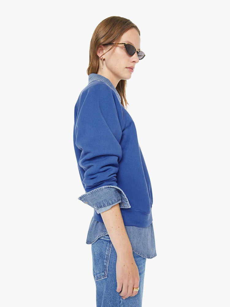 Side view of a woman in blue with  a floral block letters sweatshirt with a crewneck, ribbed hems and a slightly cropped fit.