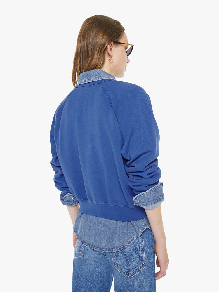 Back view of a woman in blue with  a floral block letters sweatshirt with a crewneck, ribbed hems and a slightly cropped fit.