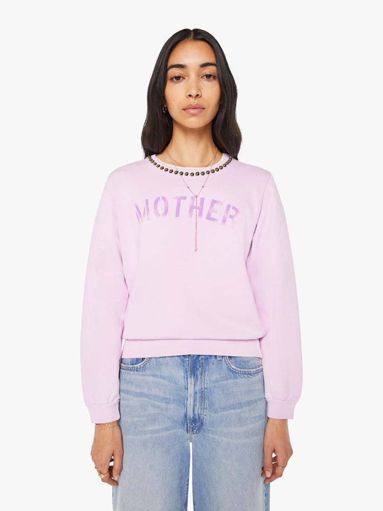 Front view of a woman in a pale orchid sweatshirt with studs along the neckline and MOTHER's name stenciled in purple across the front.