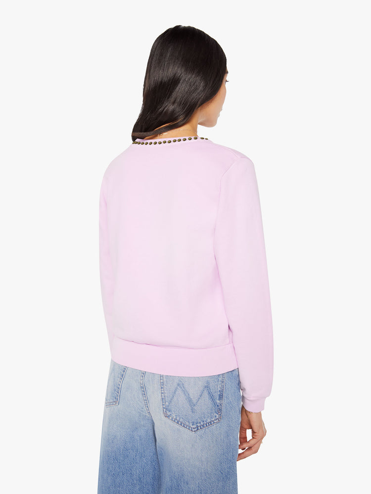Back view of a woman in a pale orchid sweatshirt with studs along the neckline and MOTHER's name stenciled in purple across the front.