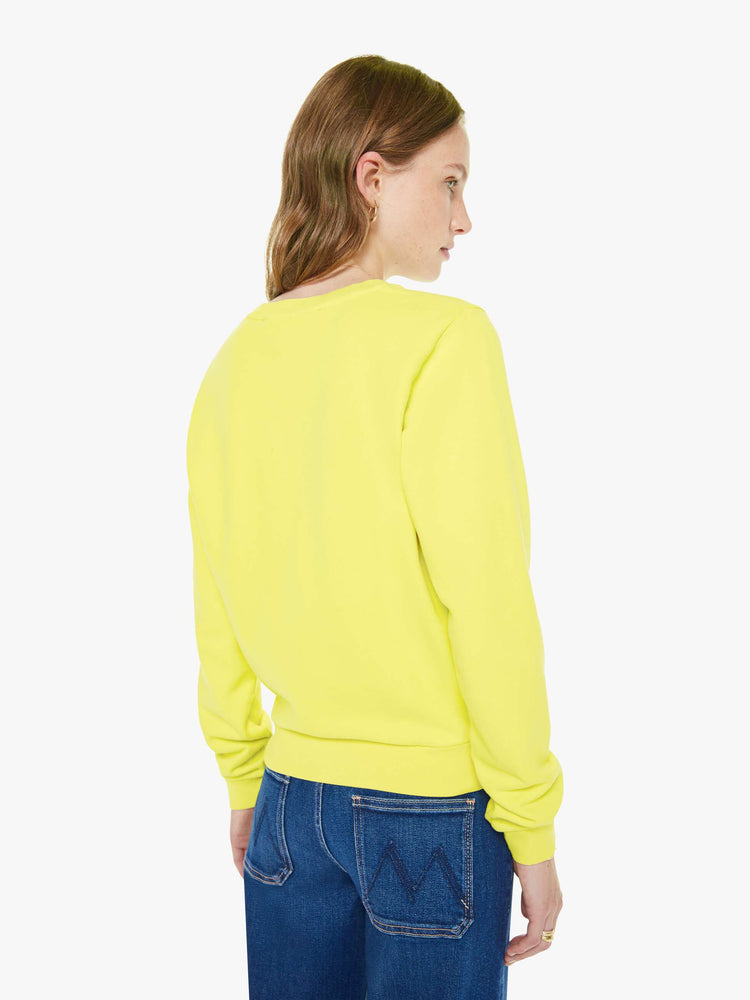 Back view of a woman in a bright yellow sweatshirt with a banana split graphic in blue, red and green on the front.