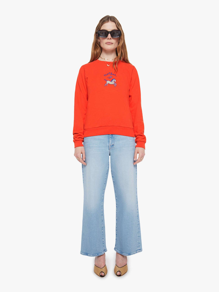 Full body view of a woman in red sweatshirt with a an embroidered horse graphic with MOTHER's name in navy on the front.