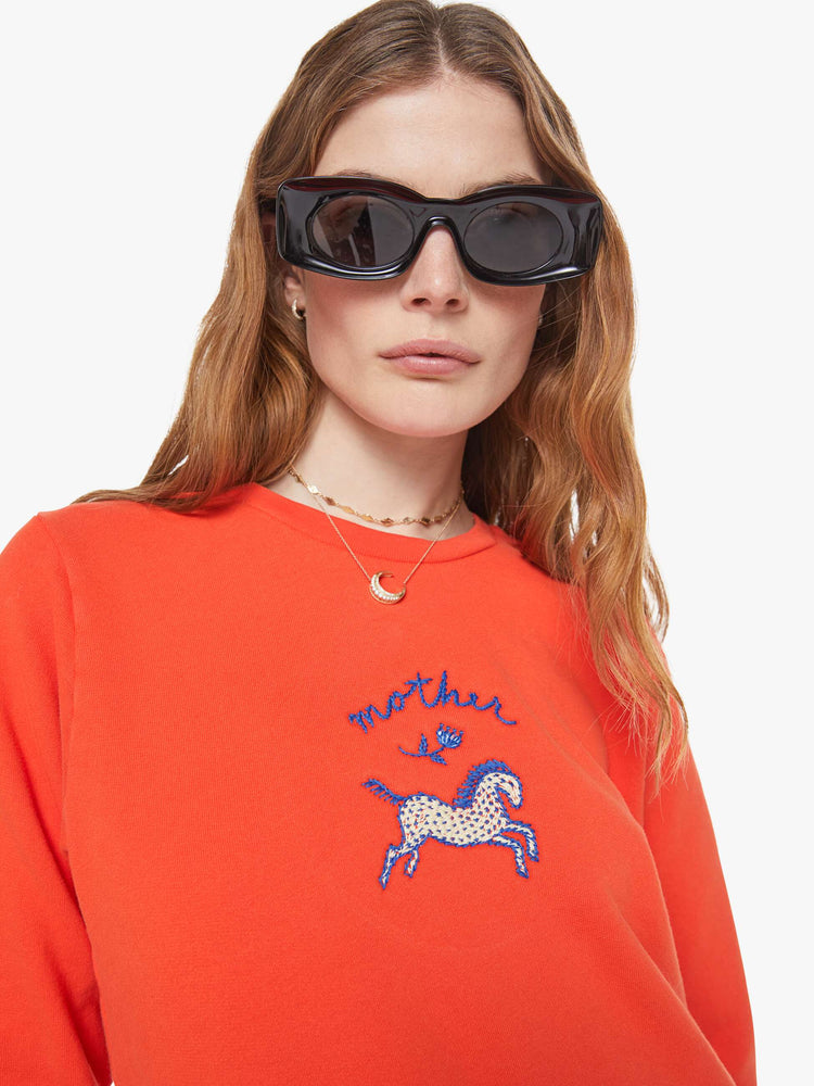 Close up view of a woman in red sweatshirt with a an embroidered horse graphic with MOTHER's name in navy on the front.
