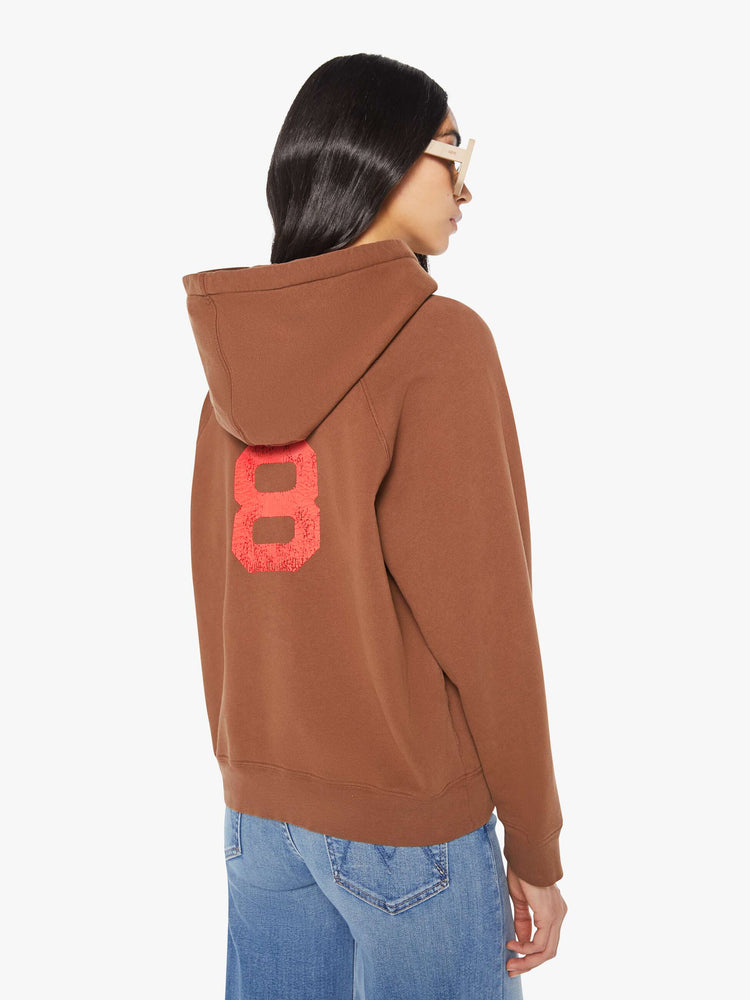 Back view of a woman in brown with a faded text graphic hoodie with an oversized patch pocket and a loose, comfortable fit.