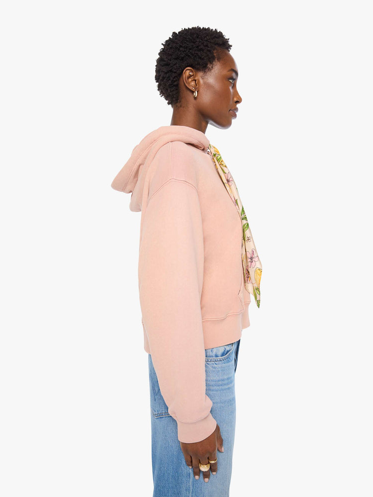 Side view of a woman in a light pink with colorful scarf drawstring hoodie with drop shoulders, ribbed hems and a front patch pocket.