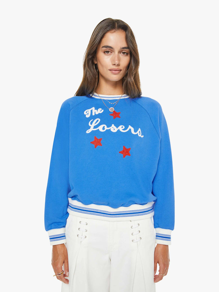 Front view of a woman in a blue sweatshirt with a white text graphic and red stars chainstitched on the front.