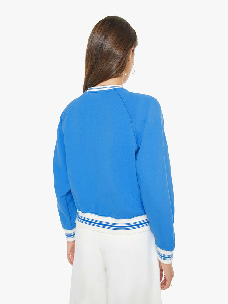 Back view of a woman in a blue sweatshirt with a white text graphic and red stars chainstitched on the front.
