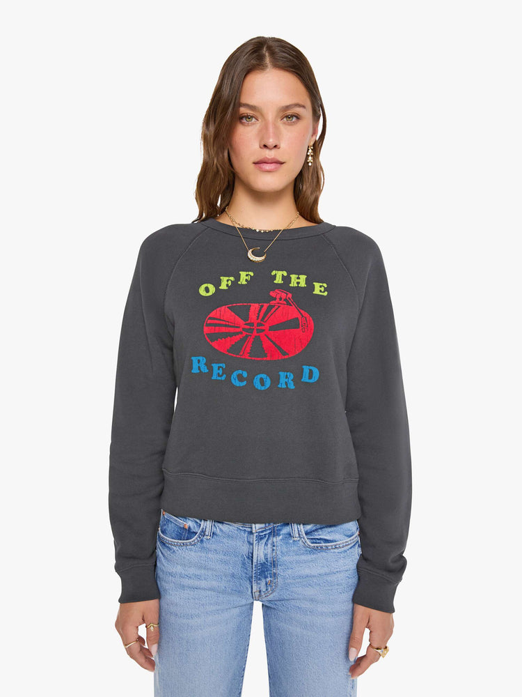 Front view of a woman in a faded grey sweatshirt features a fuzzy hot pink record graphic and text in highlighter yellow and blue on the front.
