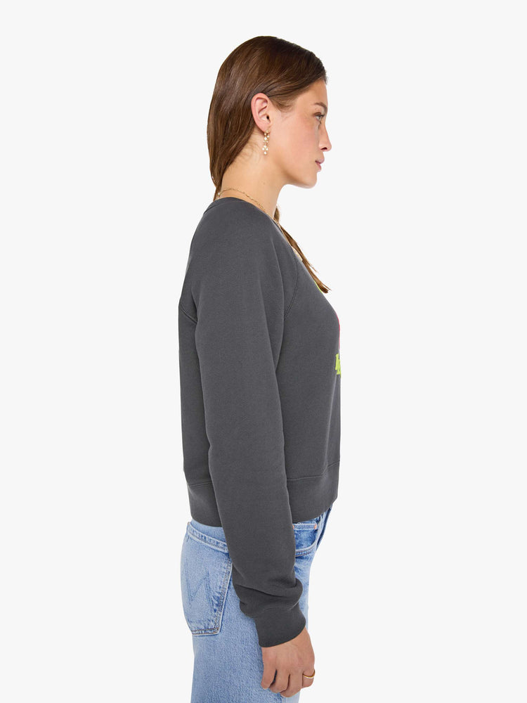 Side view of a woman in a faded grey sweatshirt features a fuzzy hot pink record graphic and text in highlighter yellow and blue on the front.