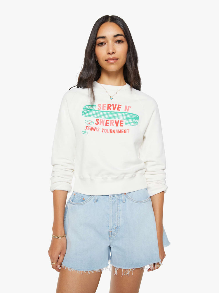 Front view of a woman in sweatshirt features a tennis tournament graphic and text in red and pink finished with a raised, velvety flocked texture.