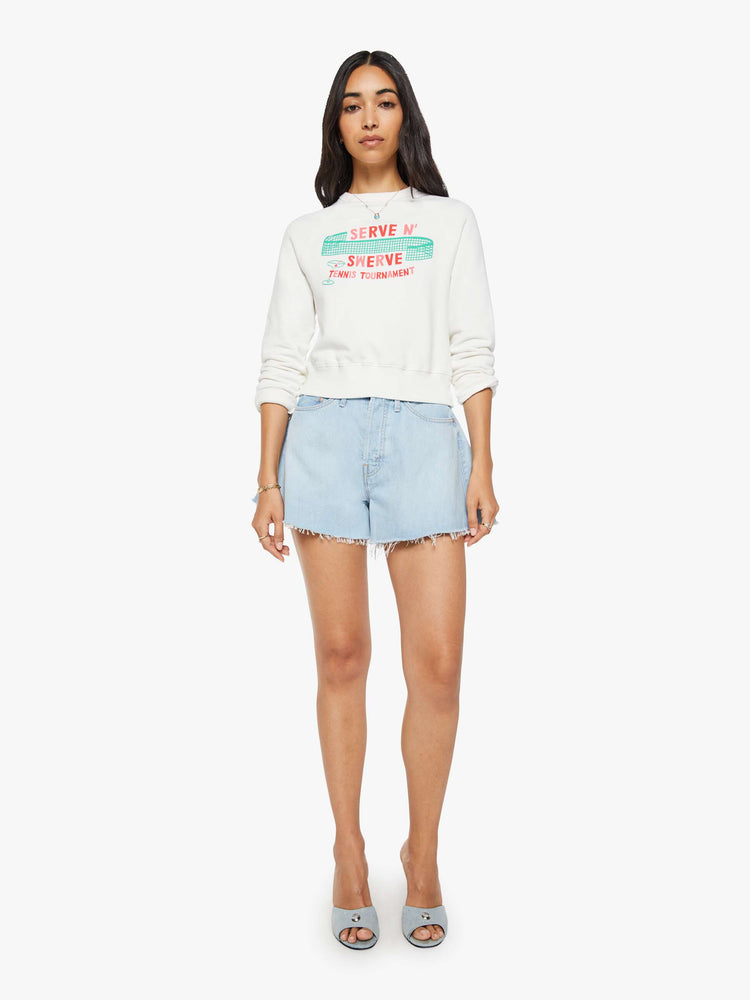 Full body view of a woman in sweatshirt features a tennis tournament graphic and text in red and pink finished with a raised, velvety flocked texture.