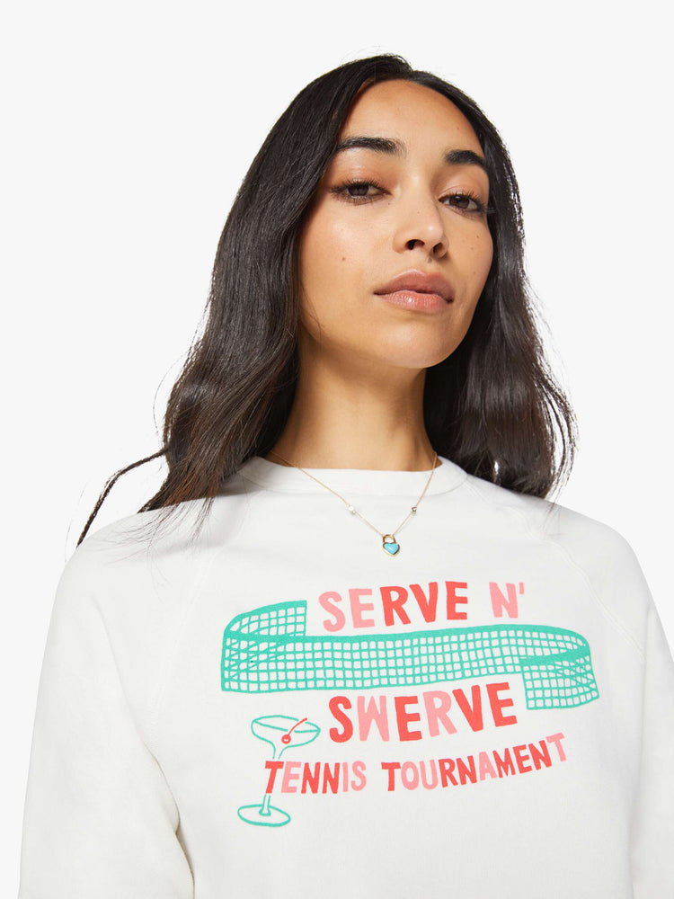 Close up view of a woman in sweatshirt features a tennis tournament graphic and text in red and pink finished with a raised, velvety flocked texture.