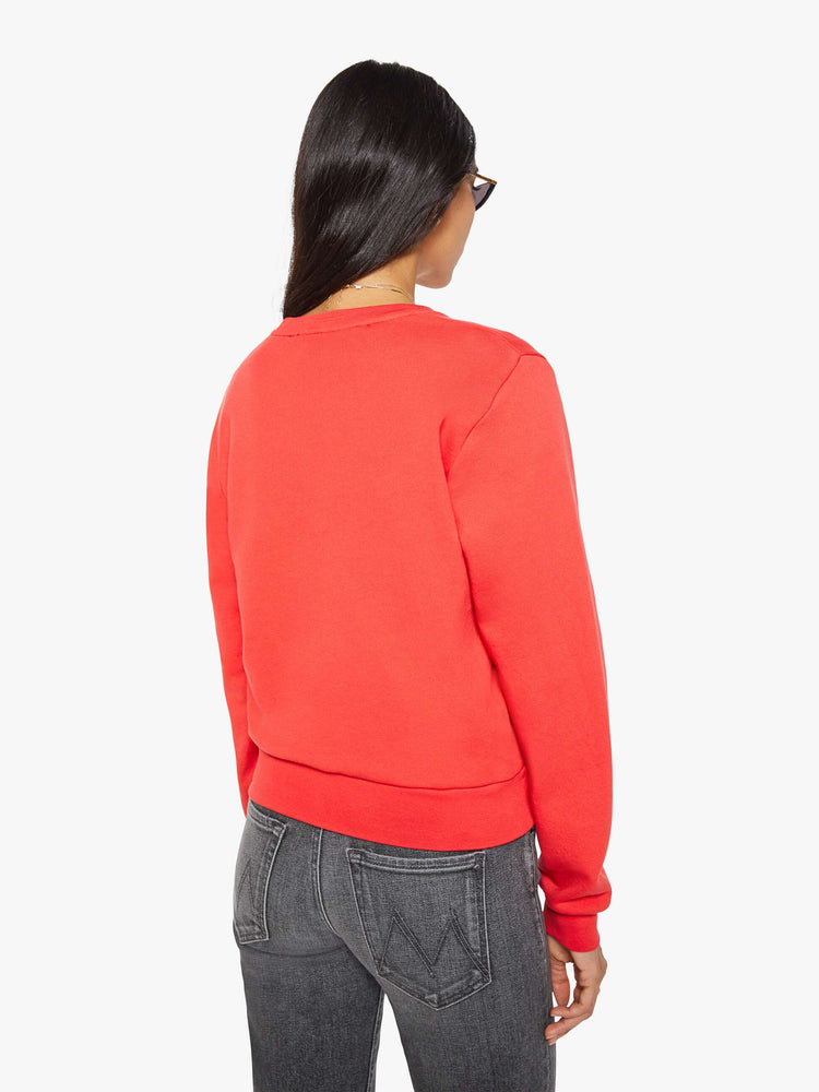 Back view of a woman in a sweatshirt is designed in faded red with a pink and light blue printed graphic and small metal studs throughout.
