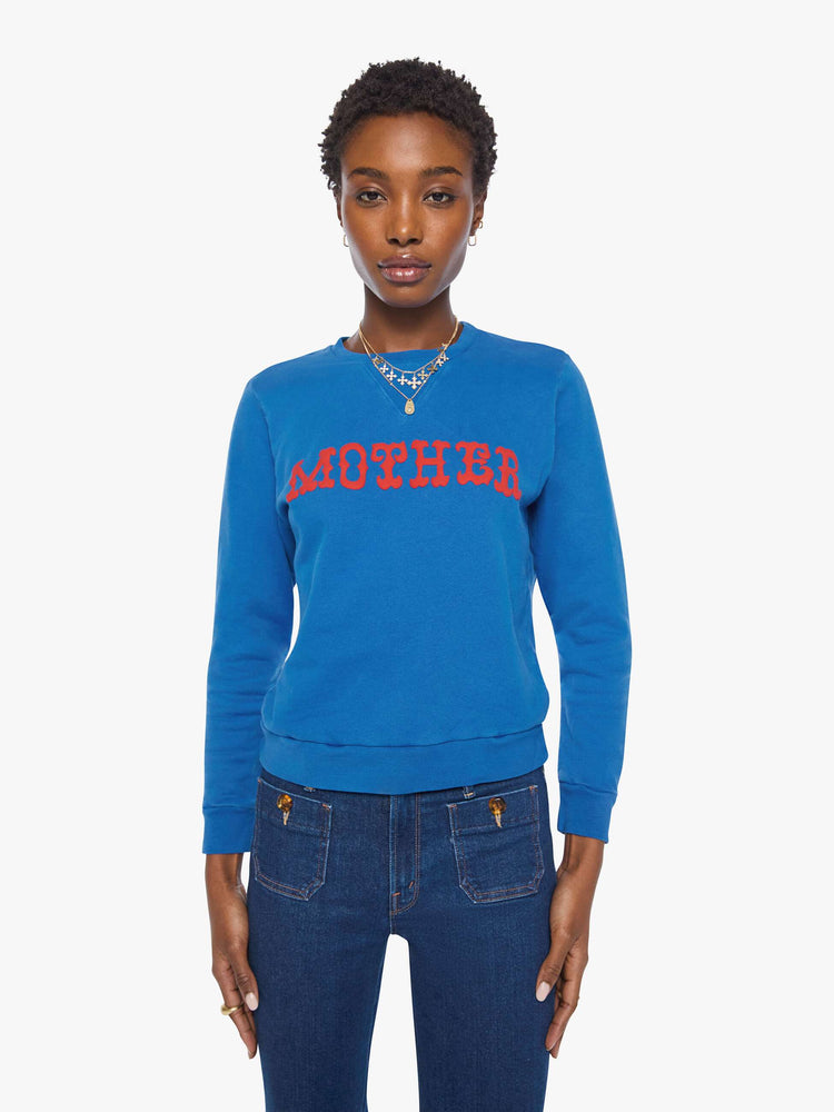 Front view of a woman in a  bright blue with MOTHER's name in red across the chest crewneck sweatshirt with ribbed hems and a loose, comfortable fit.