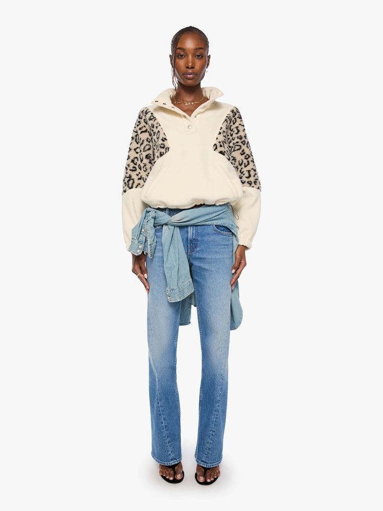 Full body view of a woman in a cream with inset cheetah print panels at the shoulders oversized fleece with a buttoned funnel neck, slit pockets and elastic hems. 