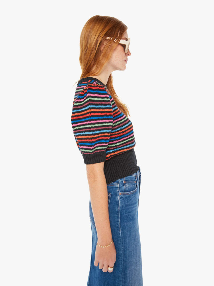 Side view of a woman knit top with a crew neck, elbow-length balloon sleeves and a thick ribbed hem in black with neon stripes.