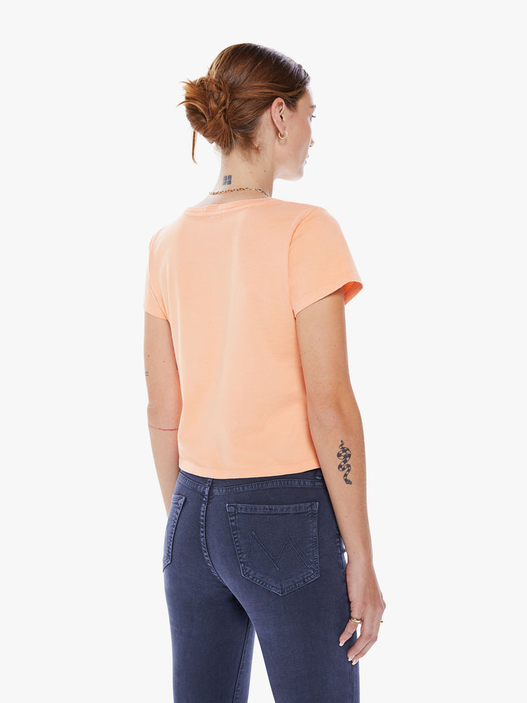 Back view of a women crewneck with short sleeves, a cropped hem and a slim fit in an orange hue with a lavender graphic.