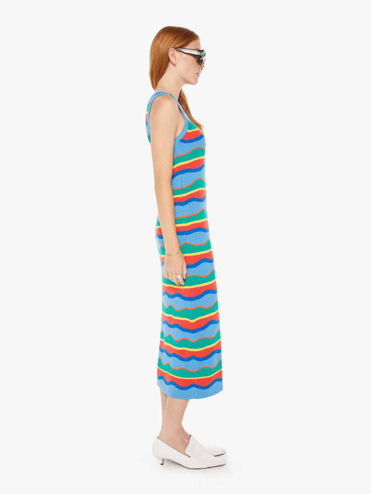 Side view of a woman striped midi dress in a rainbow of primary colors features a slim fit, scoop neck, thick straps and a calf-length hem.