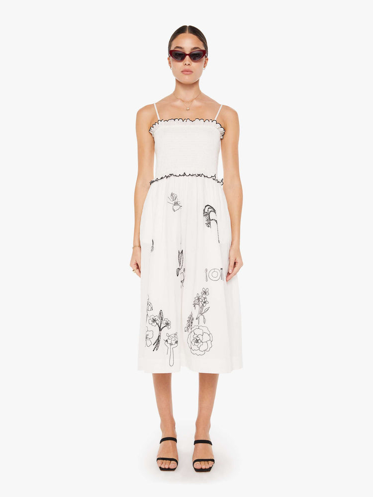 Front view of a womens white dress featuring a full skirt and contrast black embroidery details.