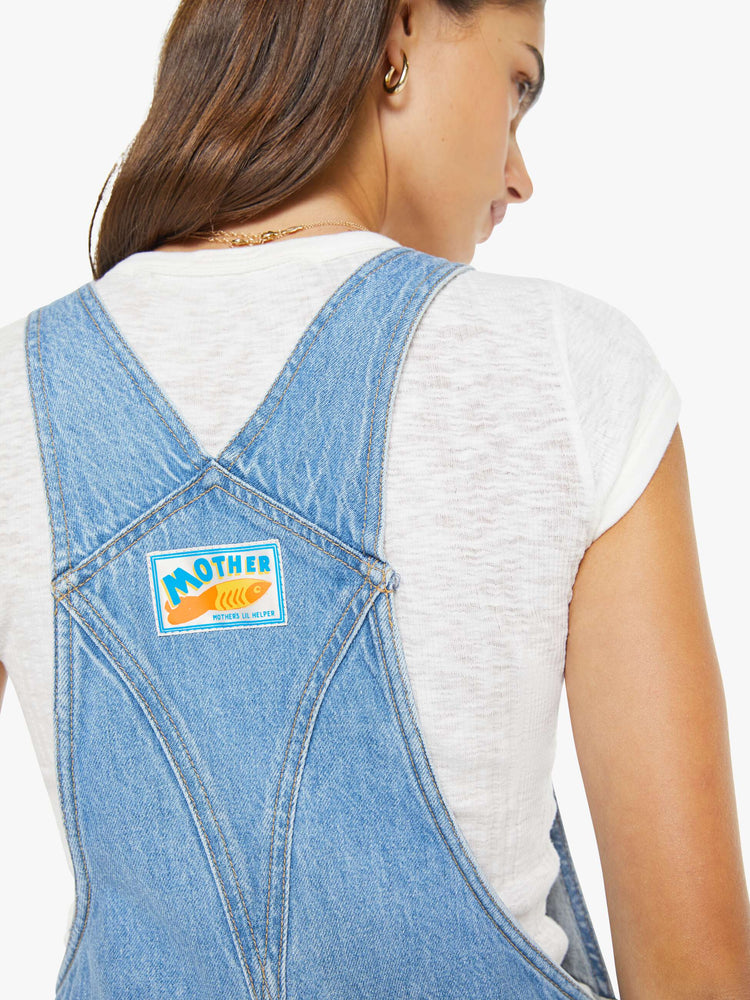 Close up view of a woman in a vintage blue denim overalls with adjustable straps, a wide, curved leg, ankle-length inseam and a clean hem. 