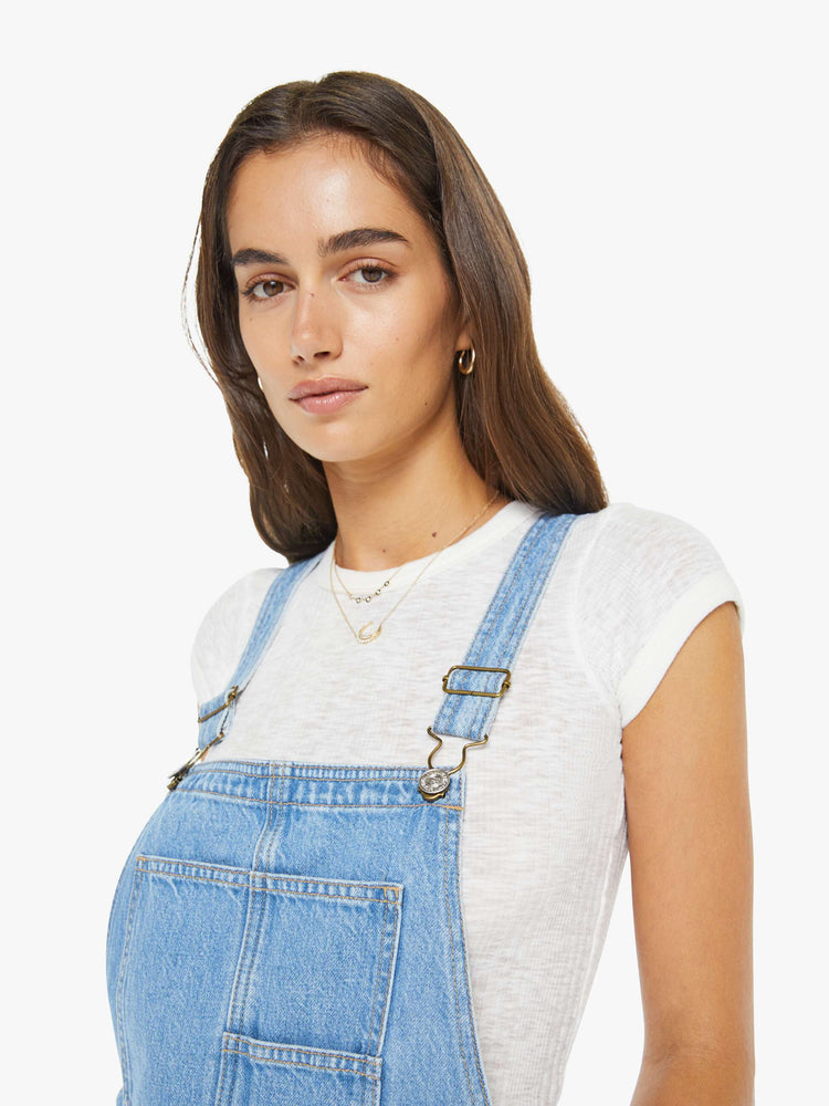 Close up view of a woman in a vintage blue denim overalls with adjustable straps, a wide, curved leg, ankle-length inseam and a clean hem. 