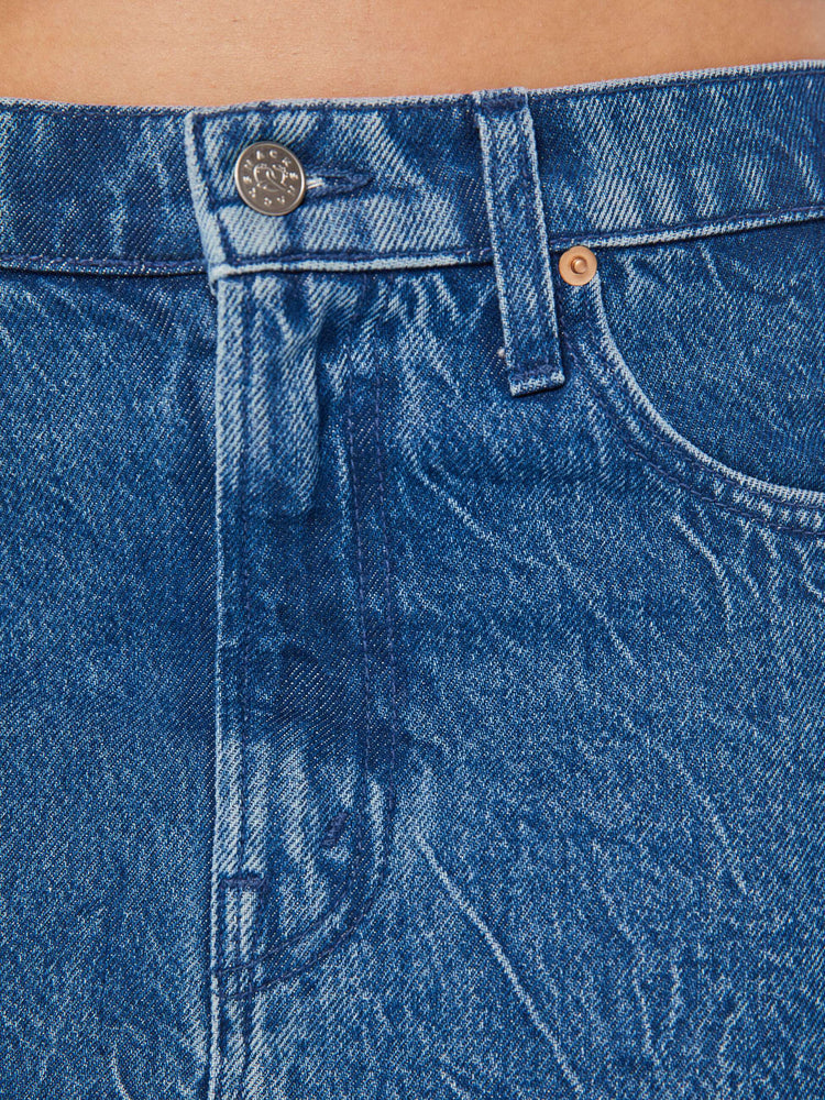 Close up swatch detail of a medium blue wash denim skirt.