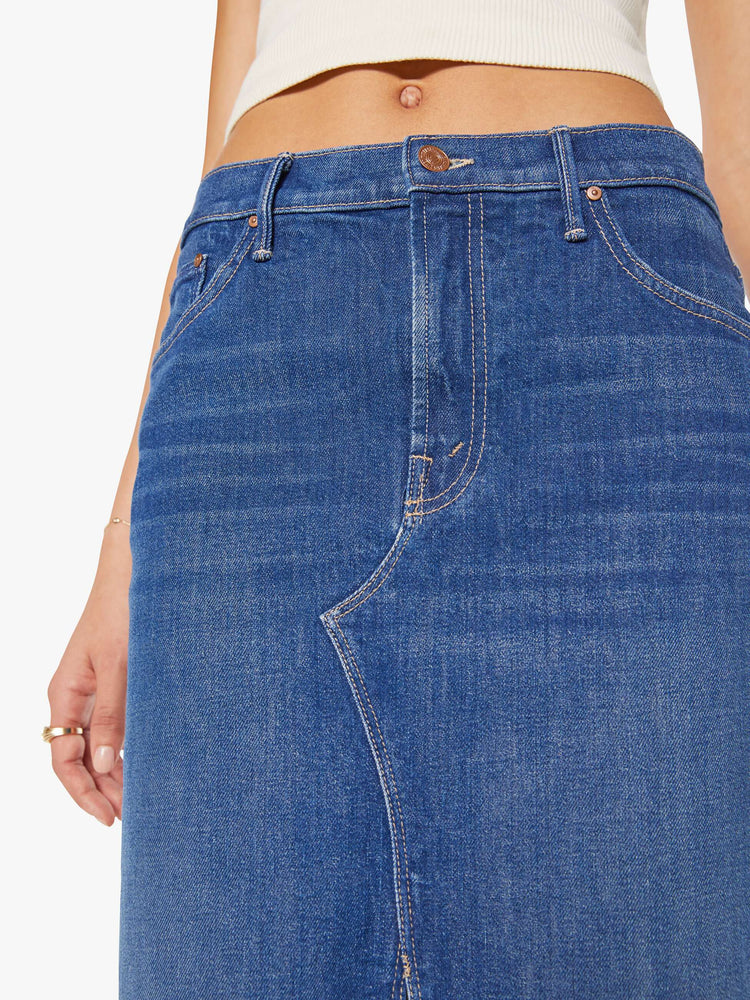 Close up view of a woman in mid blue knee- length midi skirt with a zip fly, front slit and clean hem.