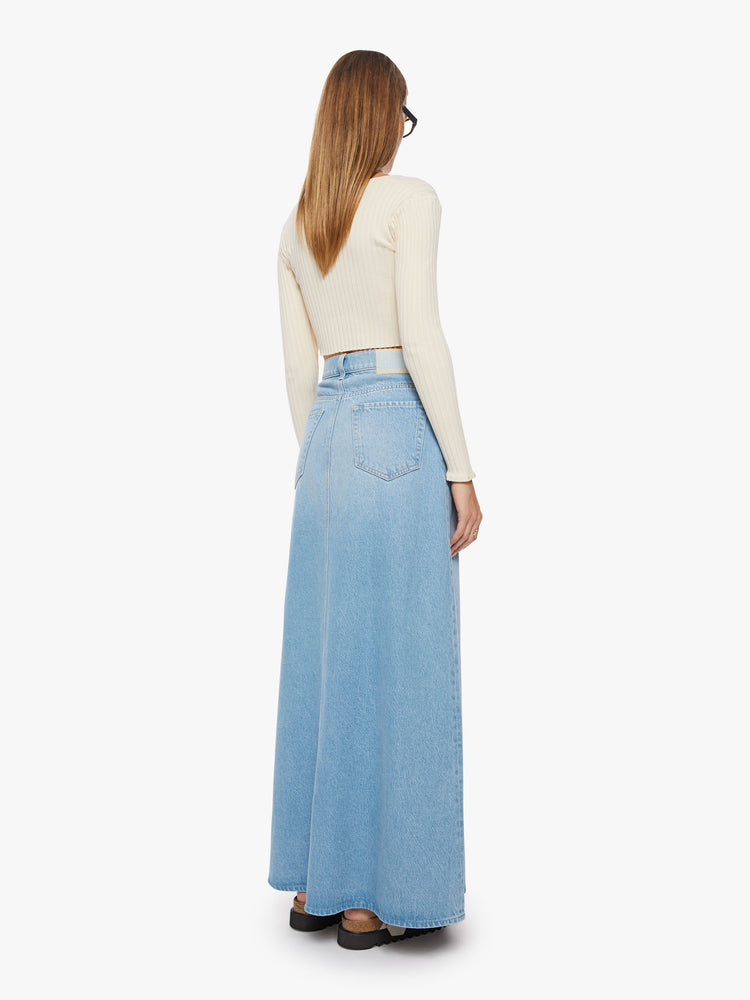 Back view of a woman high-waisted denim maxi skirt features a zip fly, loose A-line fit and a long hem in a light blue wash.