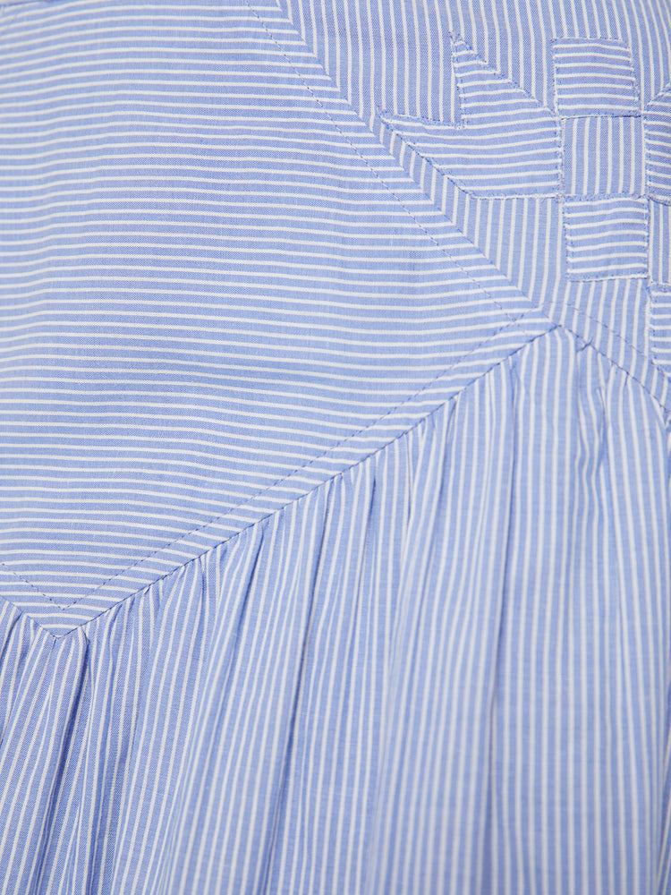 Swatch view of a high waisted midi skirt with a ruffled yoke, calf-length hem and a flowy fit in a blue and white stripe pattern with a quilted snowflake motif at the hips.