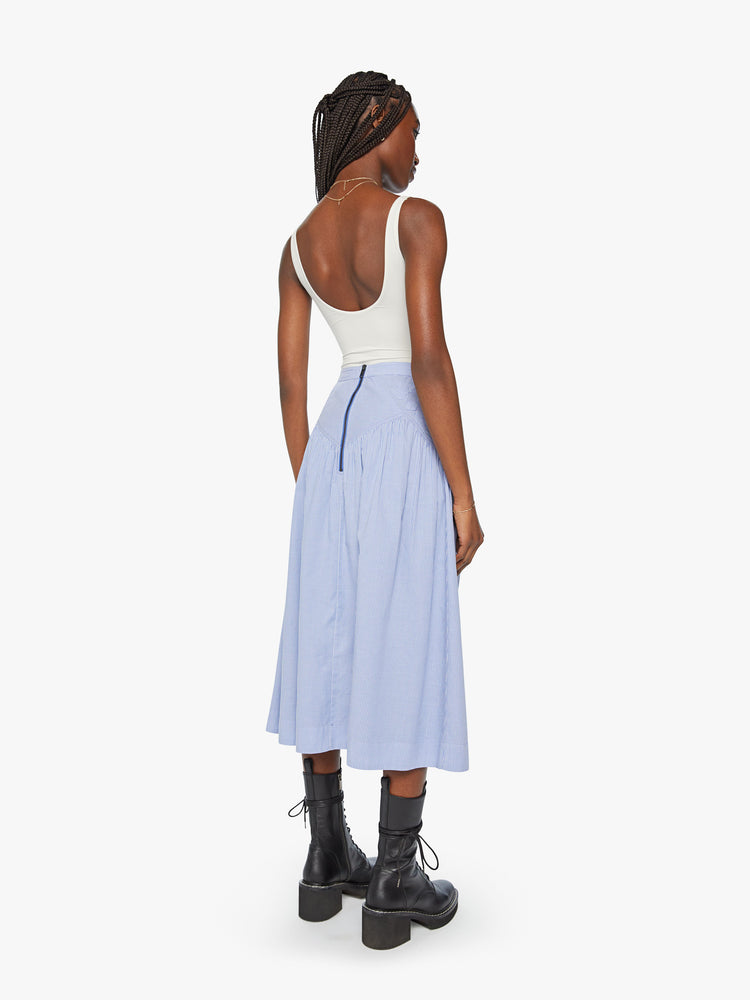 Back view of a high waisted midi skirt with a ruffled yoke, calf-length hem and a flowy fit in a blue and white stripe pattern with a quilted snowflake motif at the hips.