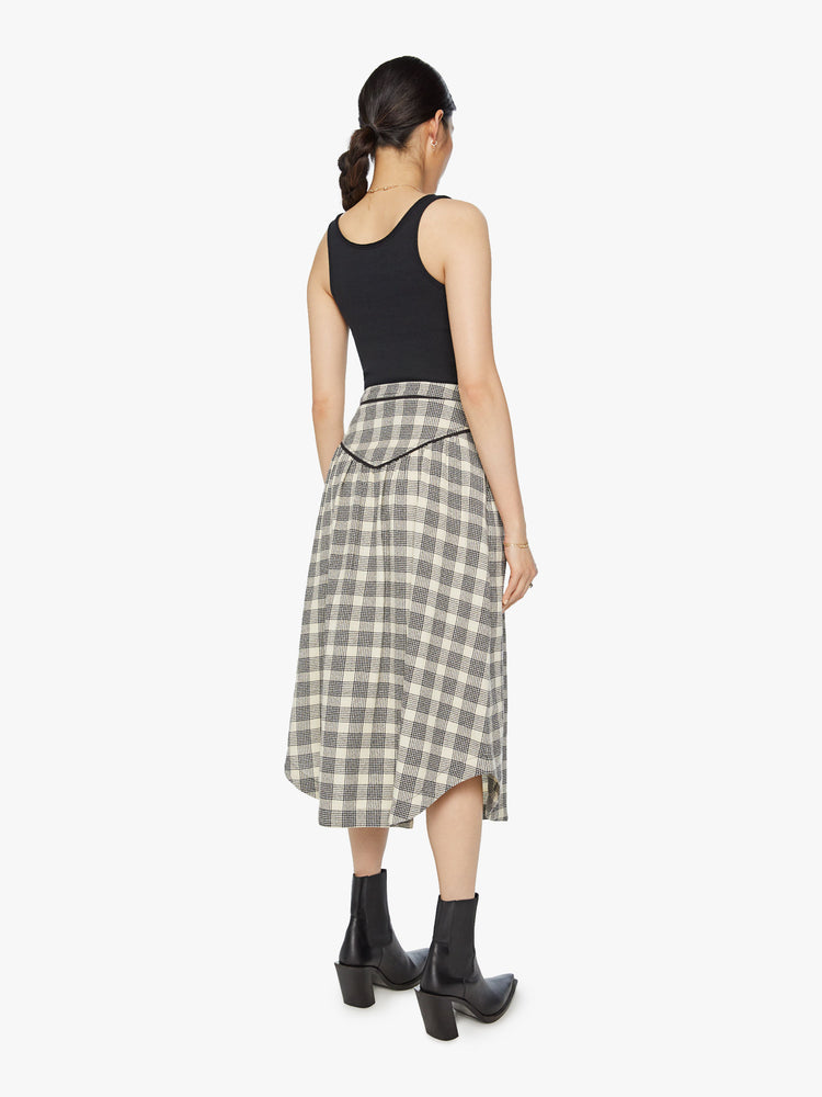 Back view of a woman midi skirt with a high rise, buttons down the front, Western-inspired detailing at the waist and a curved hem in a black and white plaid print.