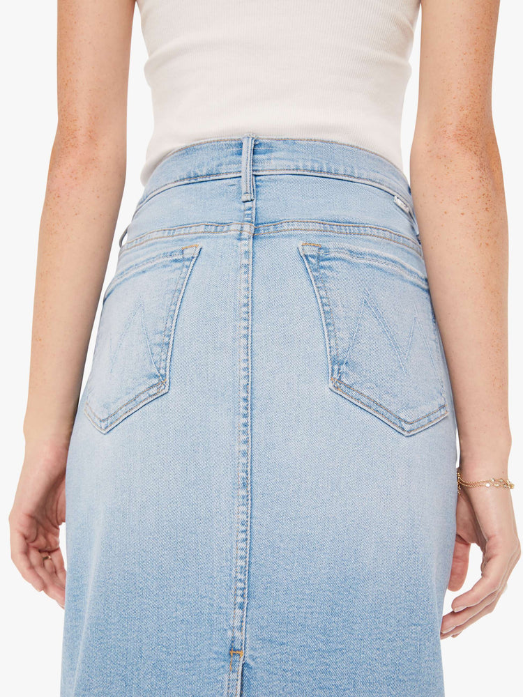 Close up view of a woman light blue denim pencil skirt with a high rise, narrow fit and a thigh-high back slit.
