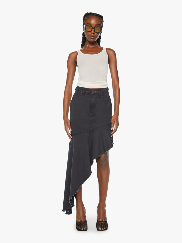 Front view of a woman high-rise skirt with an angled seam at the thigh and an asymmetrical ruffle that hits at the ankle with a frayed hem in a faded black.