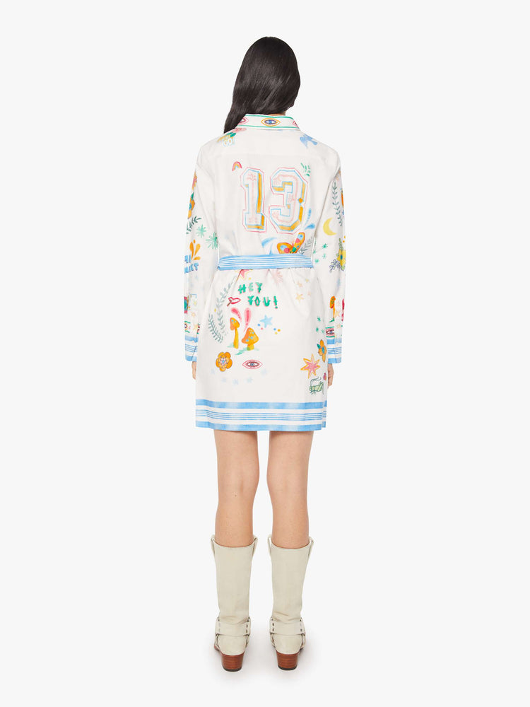 Back view of an off white with hand drawn doodles button-up dress with drop shoulders, a tied waist and a curved, thigh-length hem.