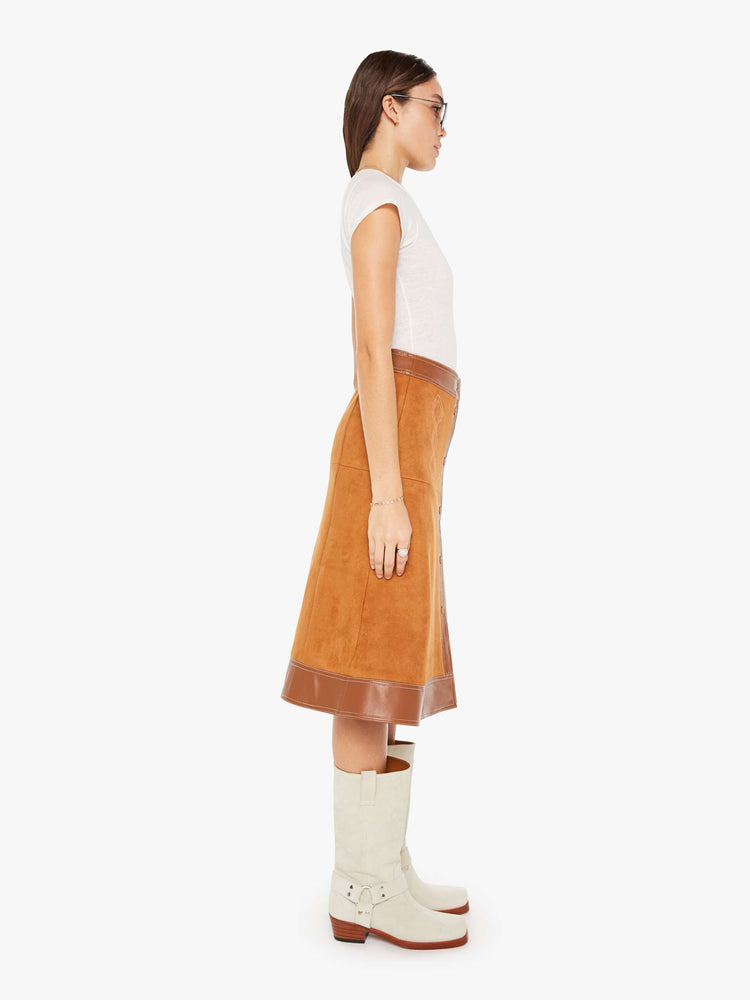 Side view of a brown faux leather skirt featuring a high rise and contrast trim.