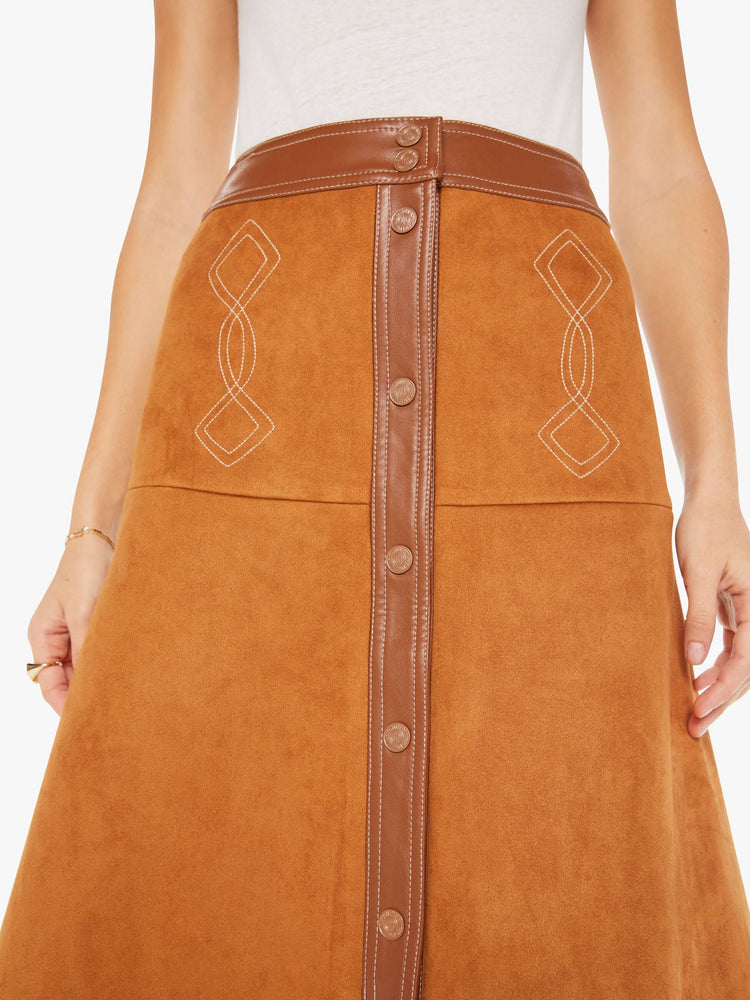 Front close up view of a brown faux leather skirt featuring a high rise and contrast trim.
