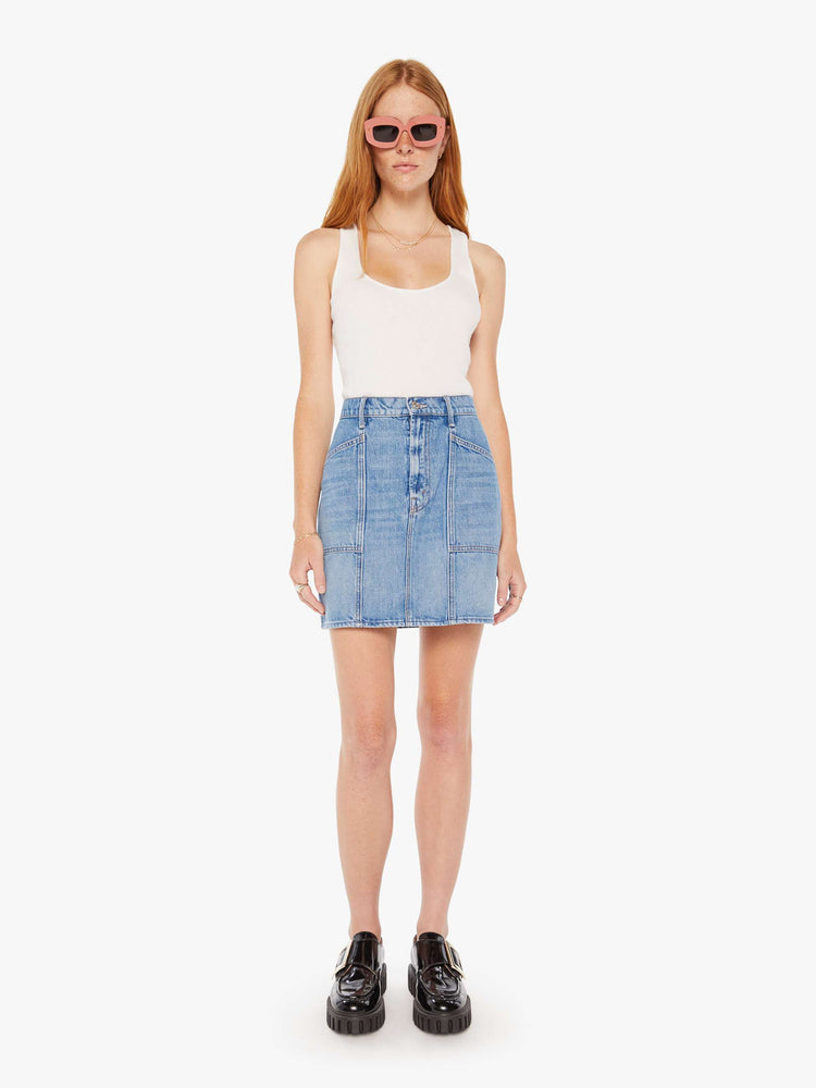 Front view of a woman denim mini skirt with a high rise, patch pockets, seams down the front and a short, thigh grazing hem in a mid blue wash. 
