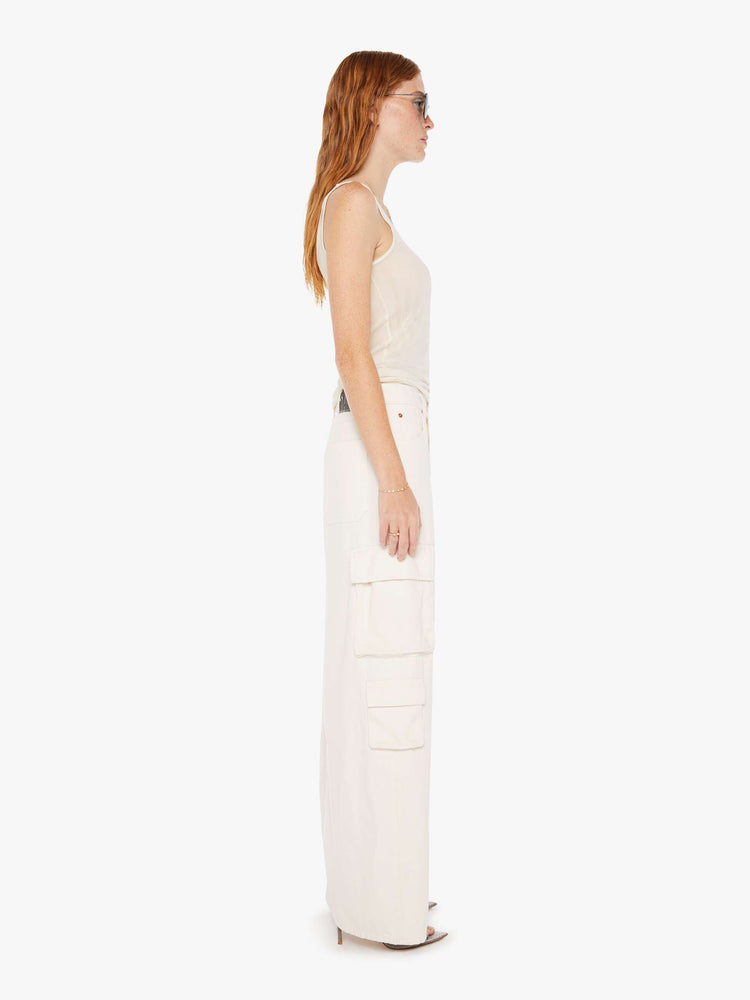 Side view of a womens off white denim skirt featuring a slouchy mid rise, cargo pockets, and a full length clean hem.