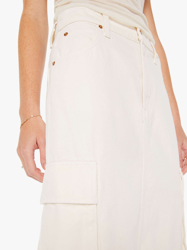 Front close up view of a womens off white denim skirt featuring a slouchy mid rise and cargo pockets.