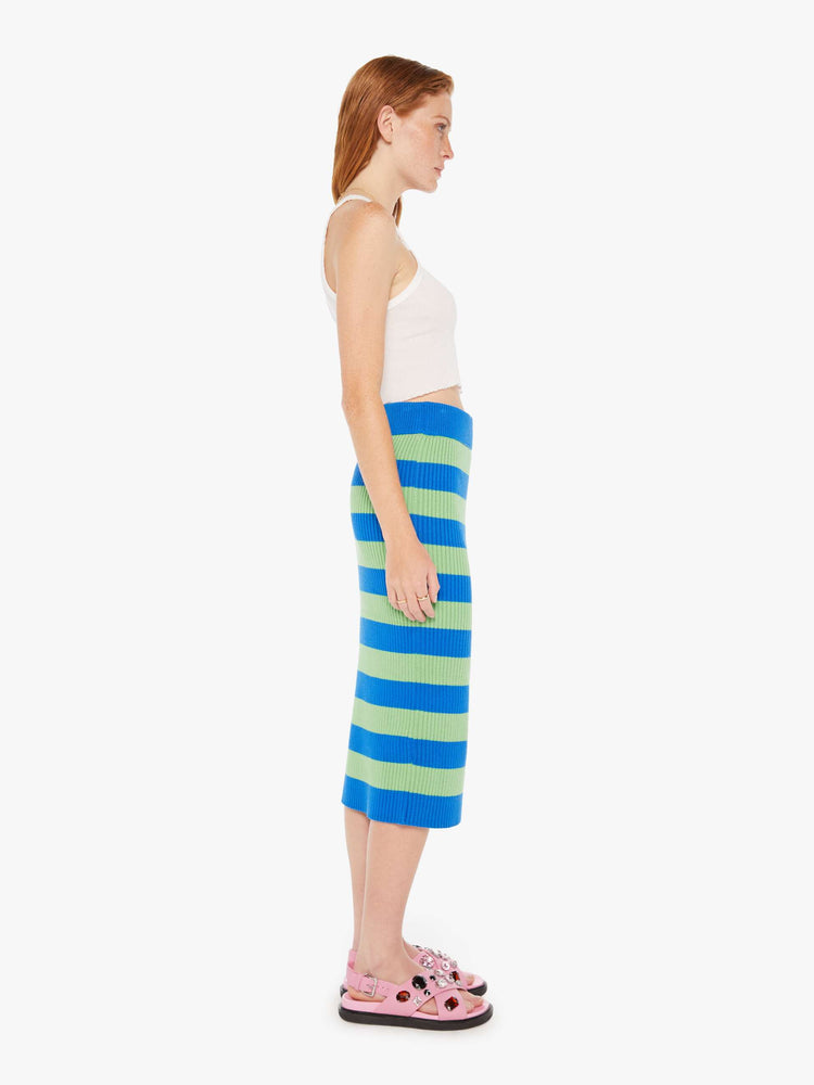 A side full body view of a green and blue striped knit skirt featuring a high rise and midi length.