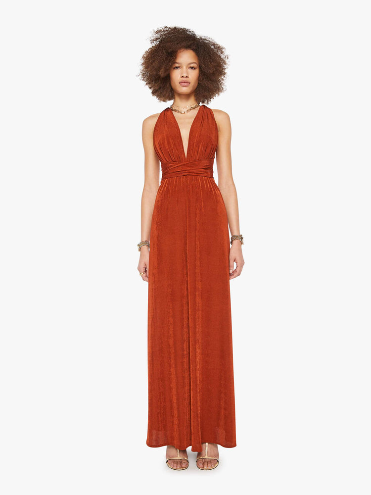 Front view of a woman in a copper V-neck maxi dress features a deep front plunge with a racerback, a tied waistband and a flowy floor-length skirt.