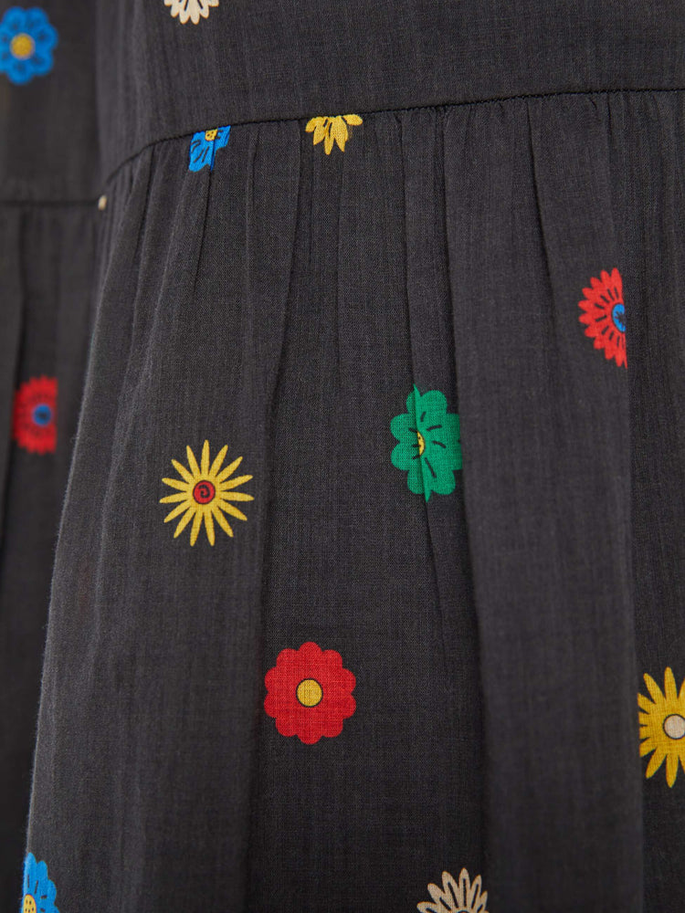 Swatch view of a woman in a black with colorful daisy print lightweight midi skirt with an elastic drawstring waistband and a ruffled tier for a loose, flowy fit.
