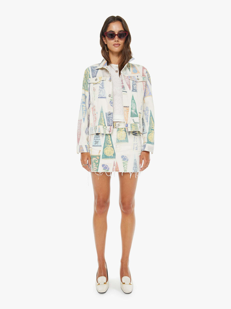 Front view of a woman in an off-white with a faded pennant print throughout low-slung mini skirt with a zip fly and a raw, frayed hem.