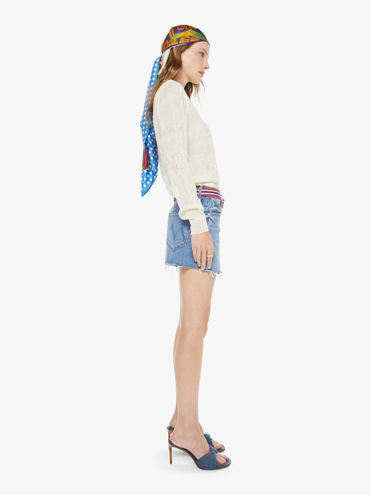 Side view of a woman in a light blue low-slung denim mini skirt with a zip fly and a raw, frayed hem.