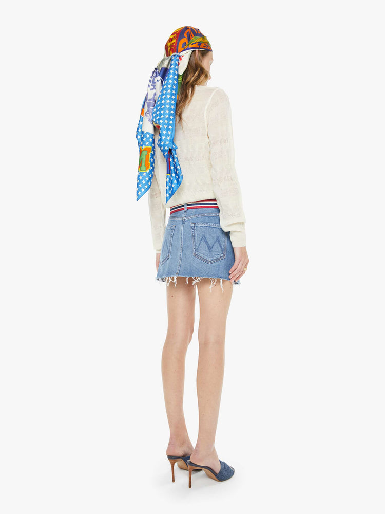 Back view of a woman in a light blue low-slung denim mini skirt with a zip fly and a raw, frayed hem.