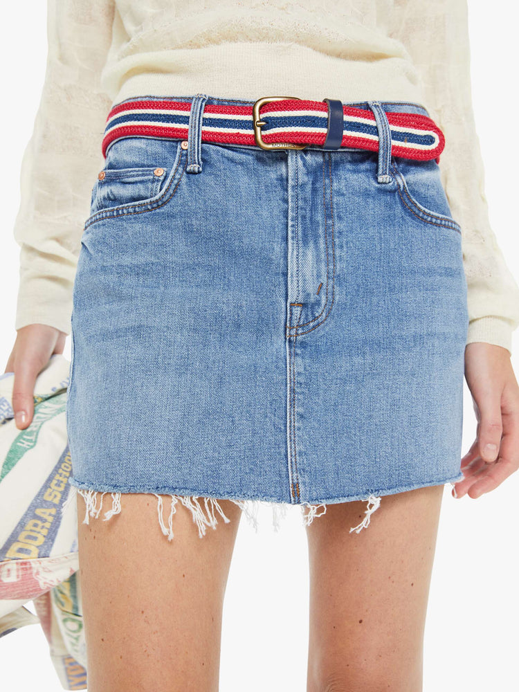 Close up view of a woman in a light blue low-slung denim mini skirt with a zip fly and a raw, frayed hem.