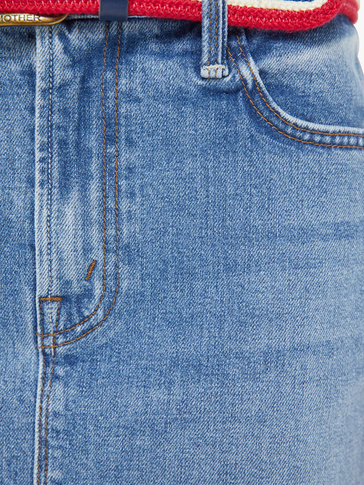 Swatch view of a woman in a light blue low-slung denim mini skirt with a zip fly and a raw, frayed hem.
