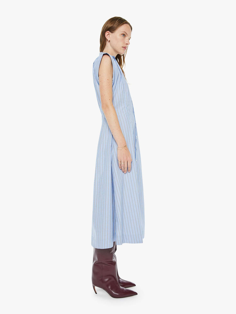 Side view of a woman in a sleeveless button-up dress with a collared neck, fitted waist and a flowy A-line skirt that hits at the calf.