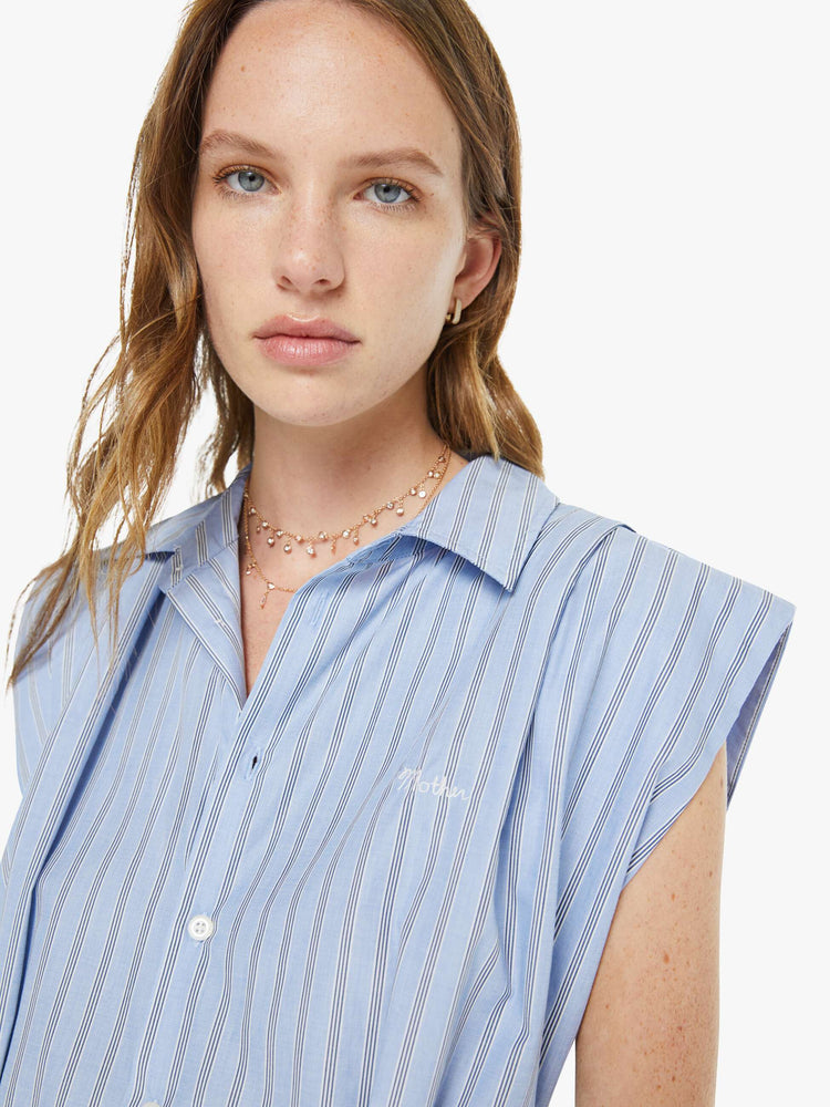 Close up view of a woman in a sleeveless button-up dress with a collared neck, fitted waist and a flowy A-line skirt that hits at the calf.