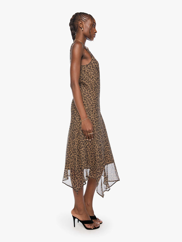 Side view of a woman in cheetah  V-neck dress with thick straps, an A-line fit and a flowy, uneven hemline that hits at the calf. 